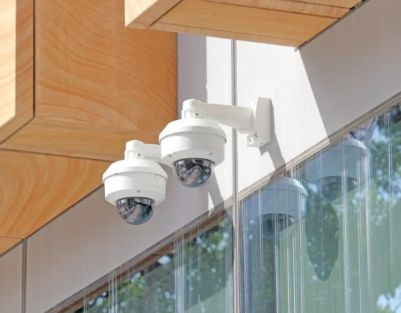 Two dome cameras on one arm at the corner of a building