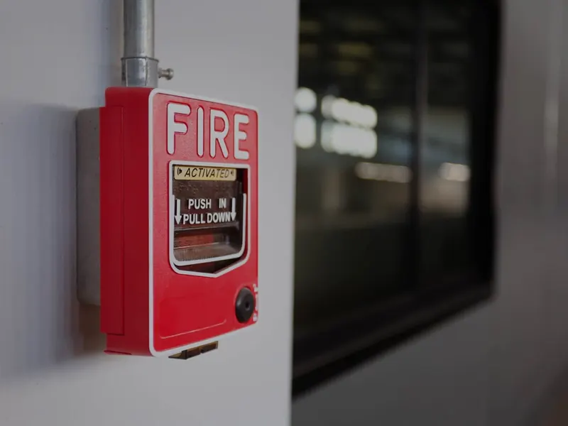 A red call point on a white wall by the entrance