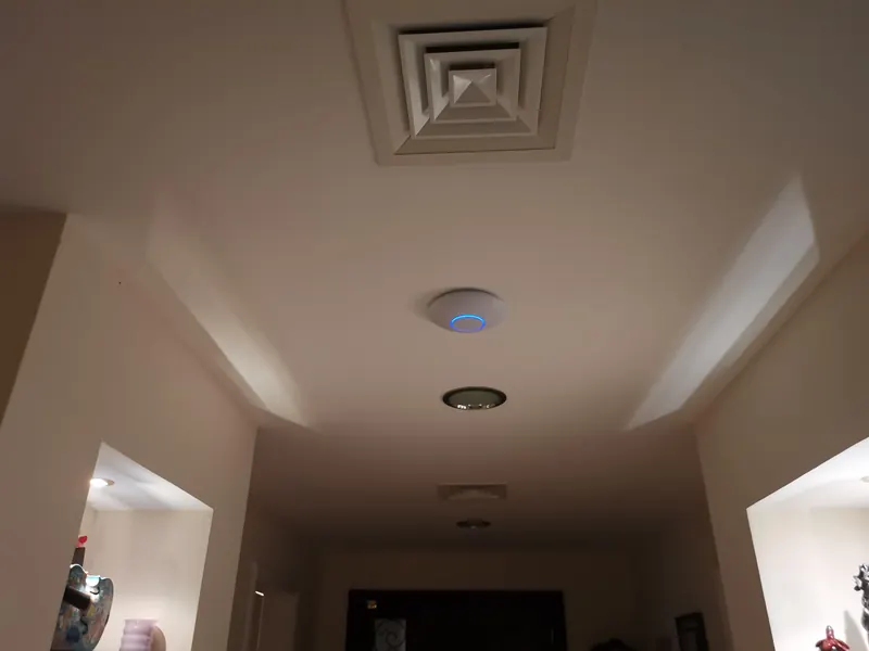 A wireless access point on the ceiling of a corridor